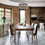 Elegant dining room with a fluted wooden table, black-and-white upholstered chairs, a statement chandelier, and marble flooring.