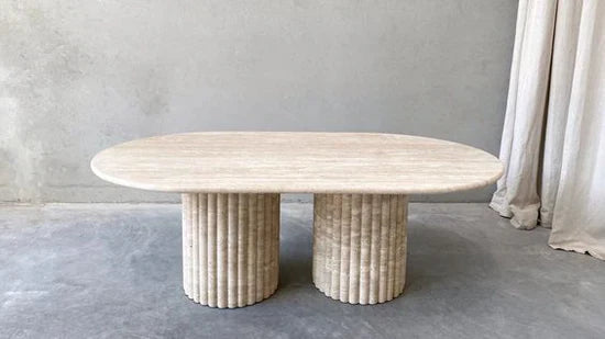 Elegant travertine oval dining table featuring a smooth, natural stone top and twin fluted column bases. This premium, minimalist table design enhances modern and contemporary interiors with its timeless style and durable craftsmanship.