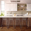 Modern kitchen with a white countertop island, featuring four sleek metal wire bar stools, wooden cabinetry, and open shelving with decorative elements.