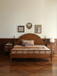 Classic wooden bed with a curved headboard and spindle details.