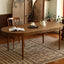 Oval wooden dining table with turned legs on geometric patterned rug