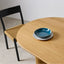 Oval light wood dining table with fluted legs