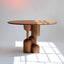 Round medium-toned wood dining table with sculptural base