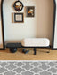 Sculptural Wood & Bouclé Bench: Black wood bench with white bouclé cushion.